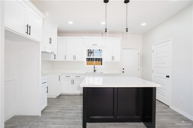 218 Kansas Ave, Weslaco, TX 78596 - kitchen with a sink, white cabinetry, a kitchen island, light wood-style floors, and light countertops