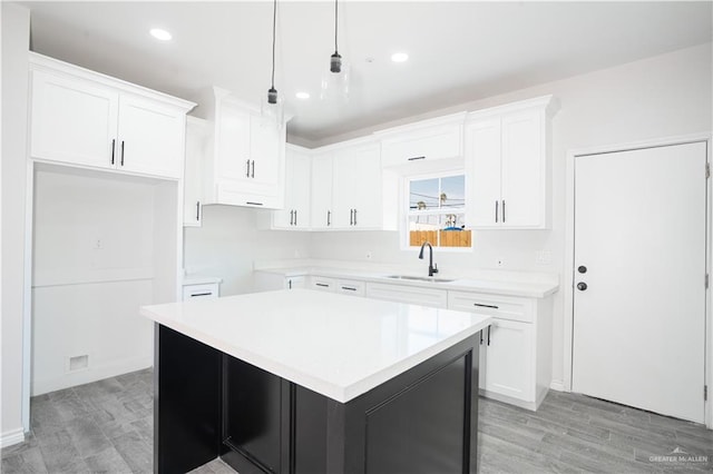218 Kansas Ave, Weslaco, TX 78596 - kitchen featuring pendant lighting, a center island, a sink, white cabinets, and light wood-type flooring