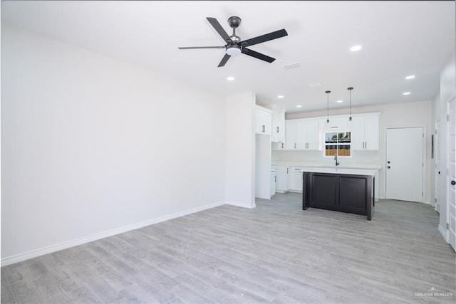 218 Kansas Ave, Weslaco, TX 78596 - kitchen with light countertops, white cabinetry, a ceiling fan, and light wood-style floors