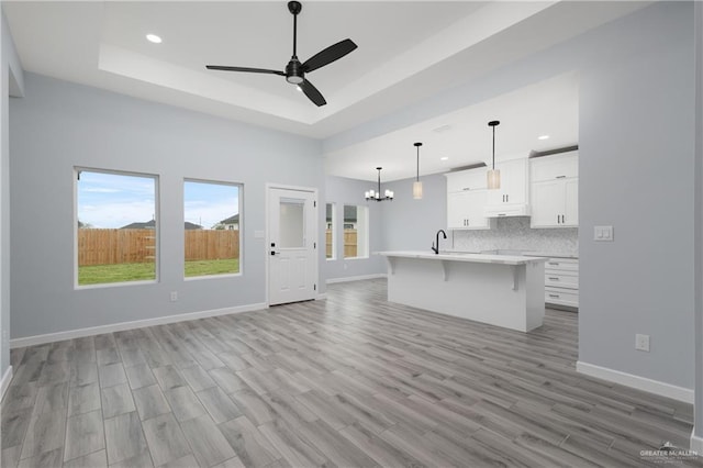 2023 Peace Dr, La Feria, TX 78559 - unfurnished living room featuring a tray ceiling, a ceiling fan, recessed lighting, a chandelier, and light wood finished floors
