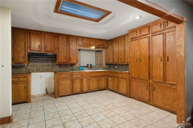 kitchen featuring light tile patterned flooring, a raised ceiling, sink, and tasteful backsplash