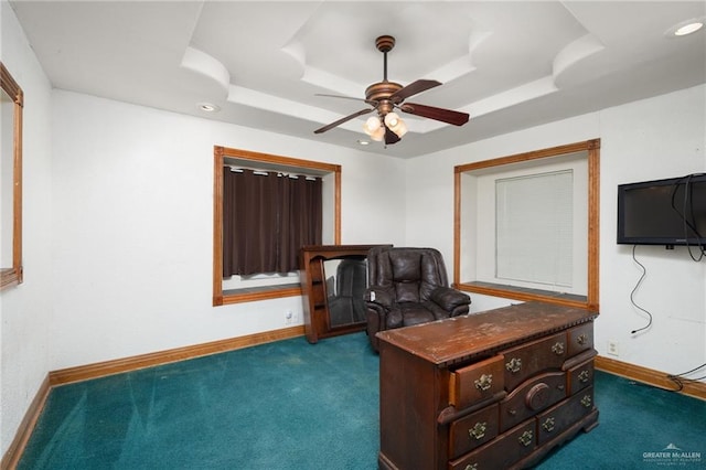 carpeted office space featuring ceiling fan and a raised ceiling