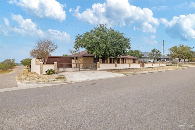 view of front of home with a garage, driveway, a fenced front yard, and a gate