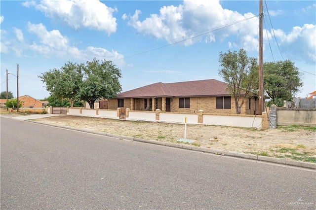 ranch-style home featuring a fenced front yard and brick siding