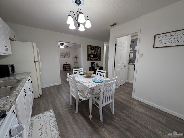 dining area with ceiling fan with notable chandelier, sink, and dark wood-type flooring