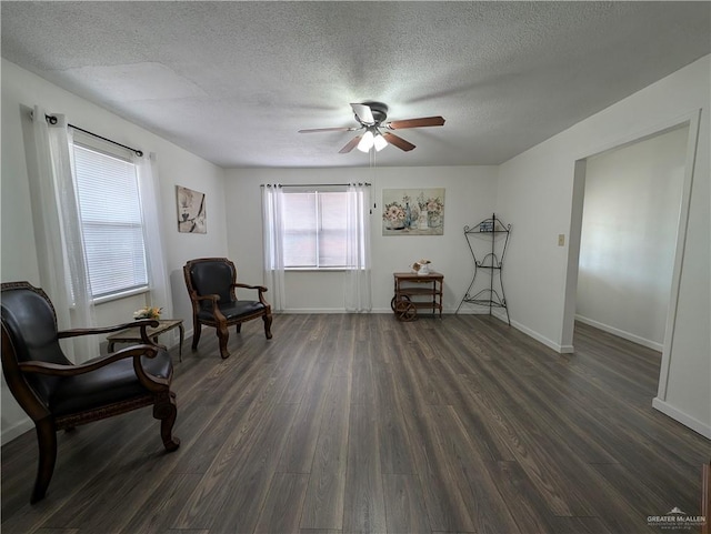 living area with dark wood-type flooring, ceiling fan, and a textured ceiling