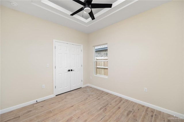 unfurnished room featuring ceiling fan, light hardwood / wood-style floors, and a raised ceiling