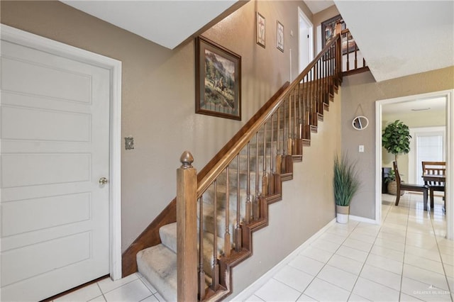 stairs with baseboards and tile patterned flooring