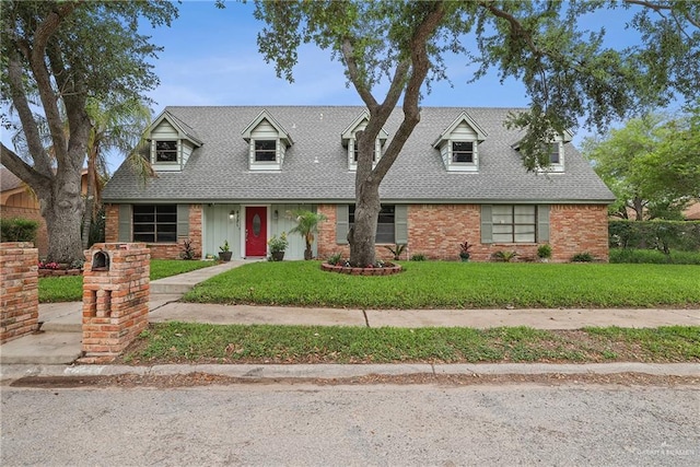 cape cod home with brick siding, a shingled roof, and a front lawn