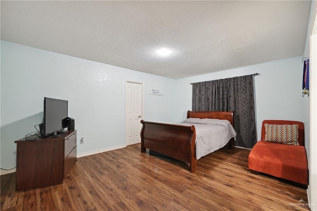 bedroom featuring baseboards, a textured ceiling, and wood finished floors
