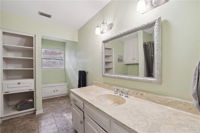 full bath featuring vanity, tile patterned floors, a textured ceiling, and visible vents
