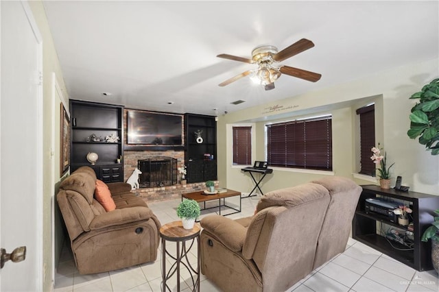 tiled living room with ceiling fan, a brick fireplace, and visible vents