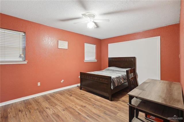 bedroom with baseboards, a textured ceiling, a textured wall, and wood finished floors