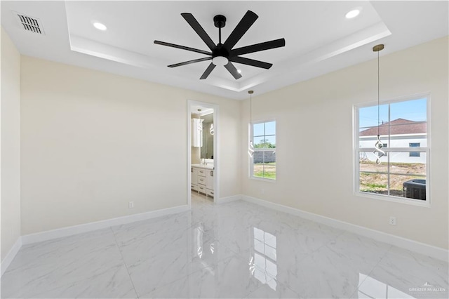 spare room featuring ceiling fan, a raised ceiling, and a wealth of natural light