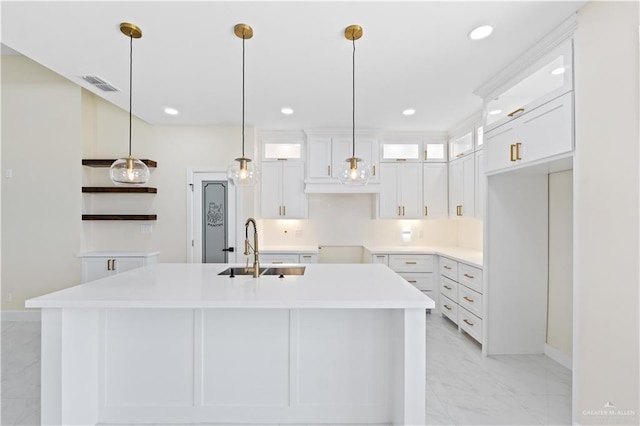 kitchen with white cabinetry, sink, hanging light fixtures, and an island with sink