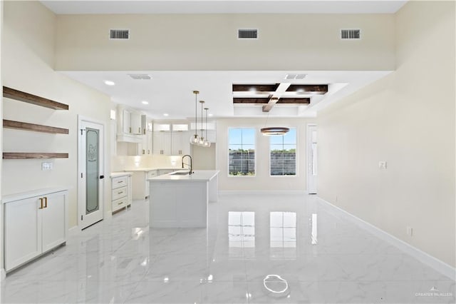 kitchen featuring coffered ceiling, sink, white cabinetry, pendant lighting, and a kitchen island with sink