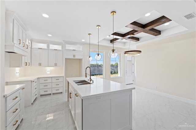 kitchen featuring a kitchen island with sink, sink, pendant lighting, and white cabinets