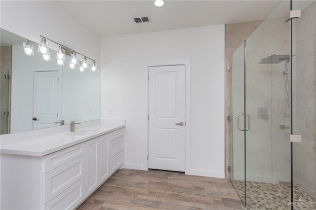 bathroom with hardwood / wood-style flooring, vanity, and a shower with shower door