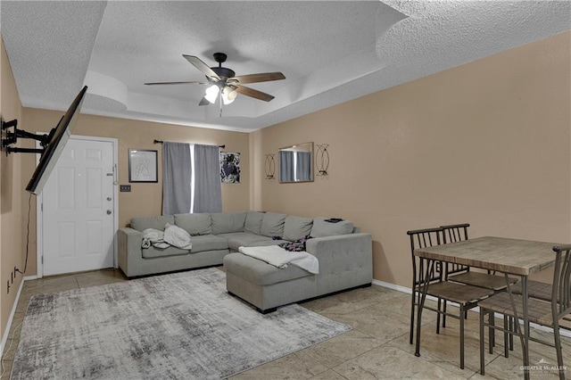 living room featuring light tile patterned floors, a textured ceiling, a raised ceiling, and ceiling fan