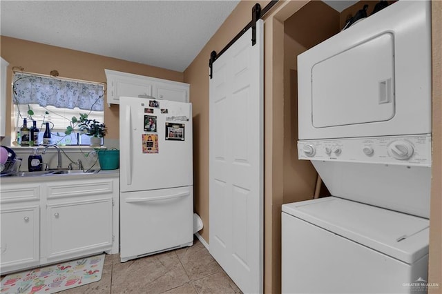 laundry room with a barn door, sink, light tile patterned floors, and stacked washer and clothes dryer