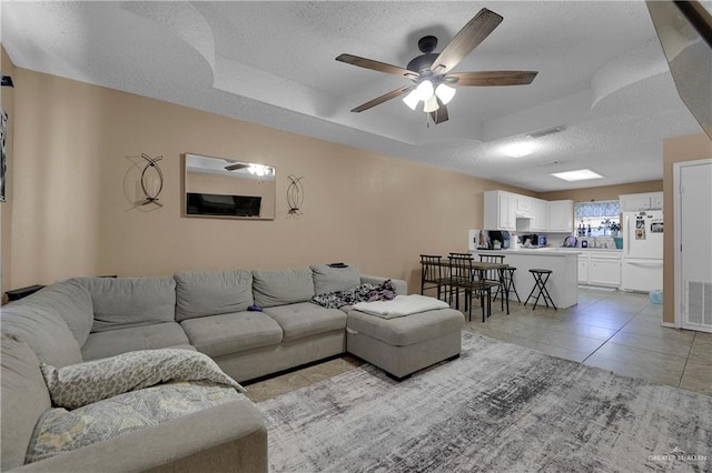 living room featuring light tile patterned floors, a textured ceiling, and ceiling fan