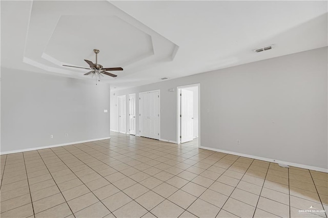 empty room with baseboards, visible vents, a raised ceiling, and a ceiling fan