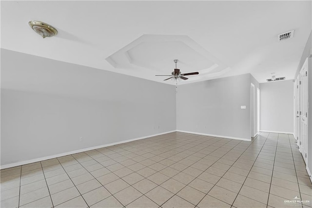 spare room featuring visible vents, a raised ceiling, baseboards, ceiling fan, and light tile patterned flooring