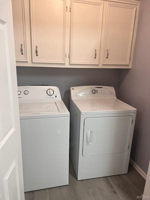 clothes washing area with cabinets, hardwood / wood-style floors, and separate washer and dryer