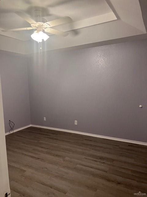 unfurnished room with dark hardwood / wood-style flooring, a raised ceiling, and ceiling fan