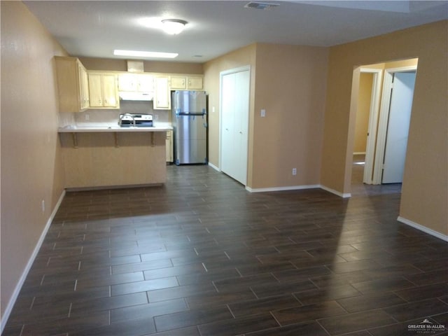 kitchen with a kitchen breakfast bar, kitchen peninsula, stainless steel refrigerator, and range