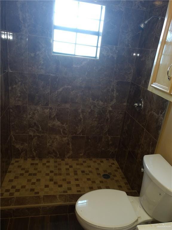 bathroom featuring a tile shower and toilet