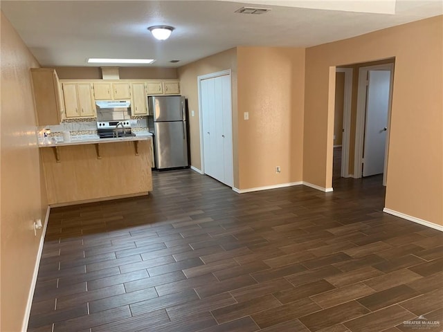 kitchen featuring sink, tasteful backsplash, kitchen peninsula, a kitchen bar, and appliances with stainless steel finishes