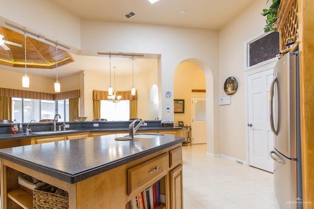 kitchen featuring pendant lighting, a center island, sink, and stainless steel refrigerator