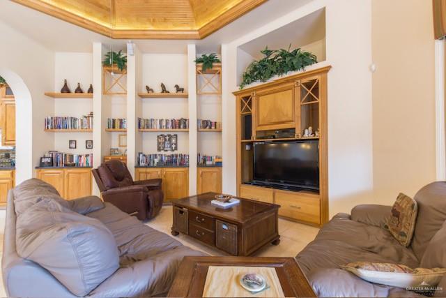 living room with a tray ceiling and built in shelves