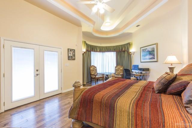 bedroom with french doors, access to outside, multiple windows, and wood-type flooring