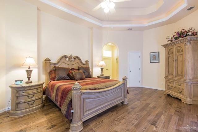 bedroom featuring dark hardwood / wood-style floors, ceiling fan, and a tray ceiling