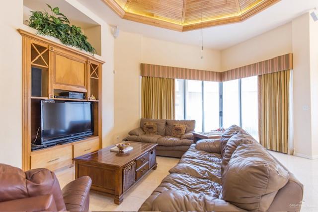 living room with a high ceiling, a raised ceiling, and ornamental molding