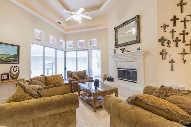 tiled living room featuring a raised ceiling, plenty of natural light, and a high ceiling