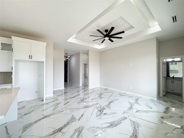 unfurnished living room with a raised ceiling and ceiling fan