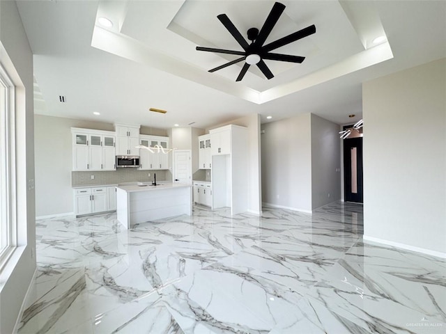 unfurnished living room with sink, a raised ceiling, and ceiling fan