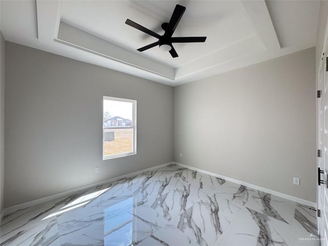 empty room featuring ceiling fan and a tray ceiling