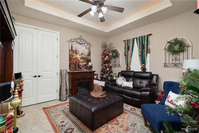 living room with ceiling fan and a raised ceiling