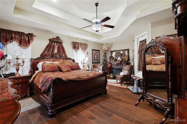 bedroom featuring a tray ceiling, ceiling fan, and dark hardwood / wood-style flooring