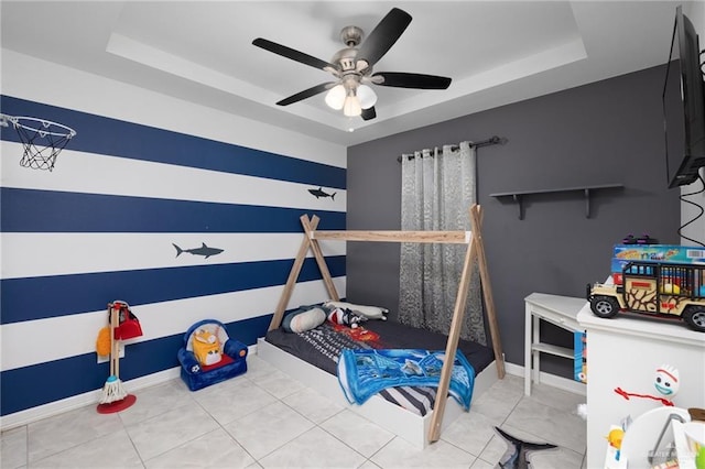 bedroom featuring ceiling fan, tile patterned flooring, and a tray ceiling