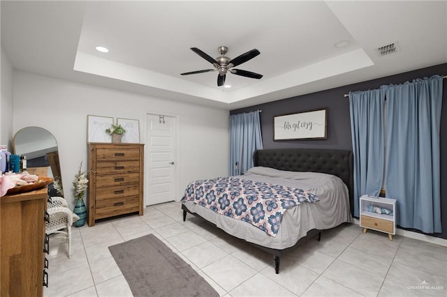 bedroom featuring ceiling fan, light tile patterned flooring, and a tray ceiling