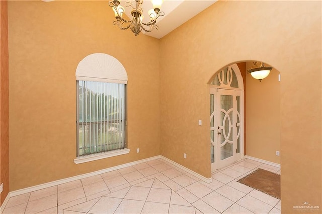 tiled spare room with an inviting chandelier