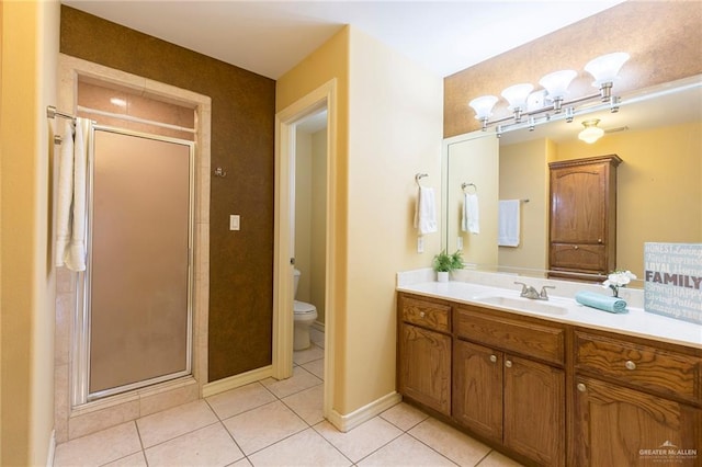 bathroom featuring tile patterned flooring, vanity, toilet, and a shower with door