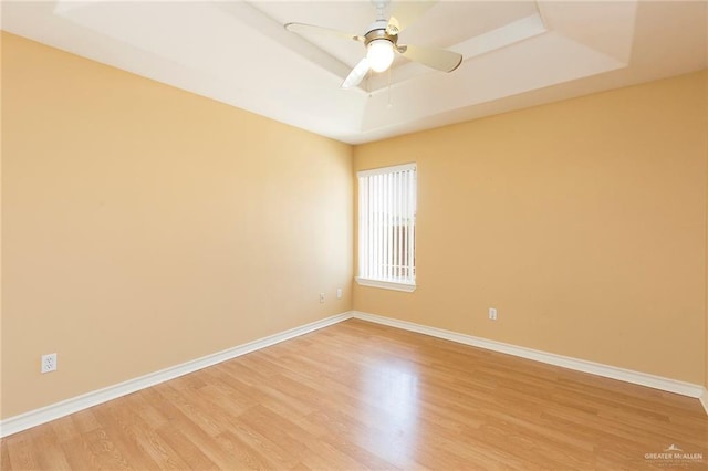 spare room featuring hardwood / wood-style flooring, ceiling fan, and a tray ceiling