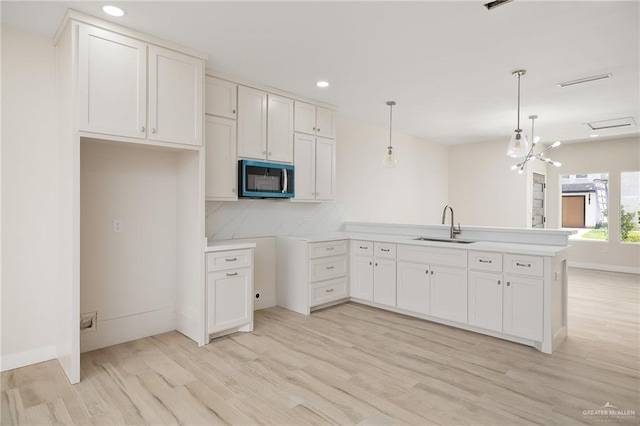 2508 E Solar Dr, Mission, TX 78501 - kitchen with stainless steel microwave, a peninsula, a sink, light wood-style flooring, and recessed lighting