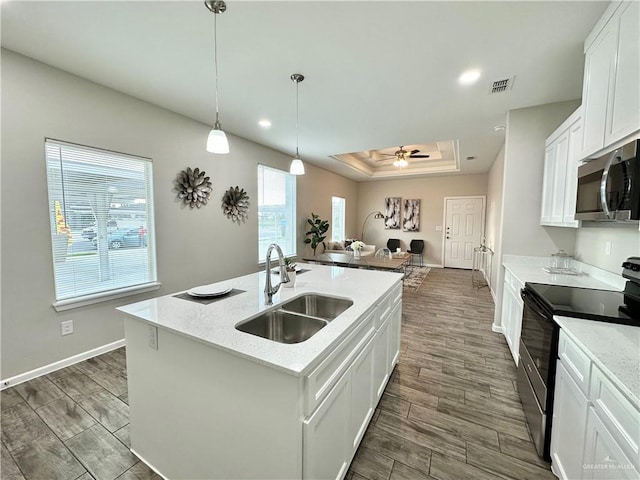 kitchen with sink, white cabinetry, light stone counters, a center island with sink, and stainless steel appliances